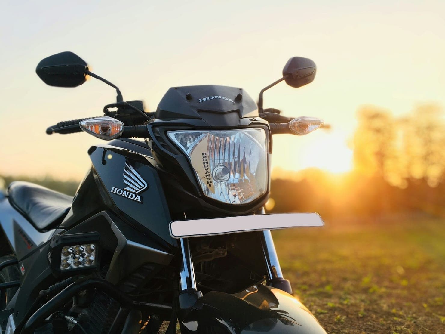 Moto Honda preta vista de frente ao entardecer